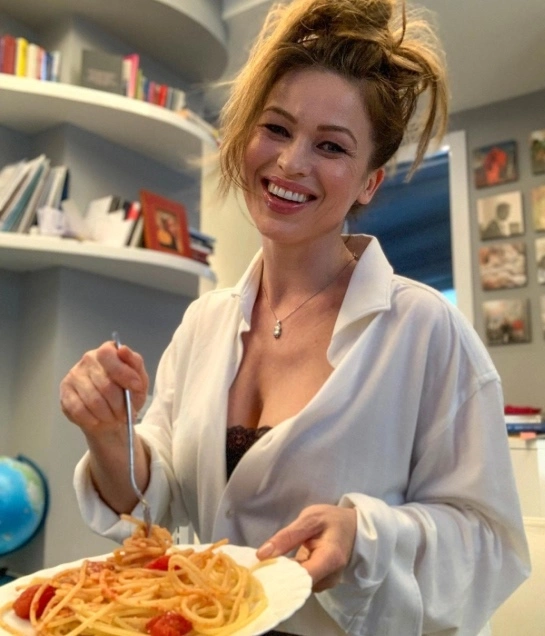 Yulia Mayarchuk in a homemade white bathrobe with a plate of Italian pasta
